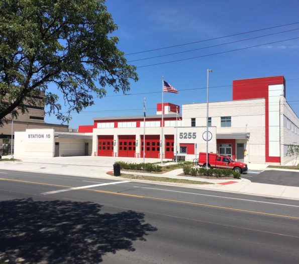 white fire station with red apparatus bays doors and front entrance leading into Alexandria Fire Station