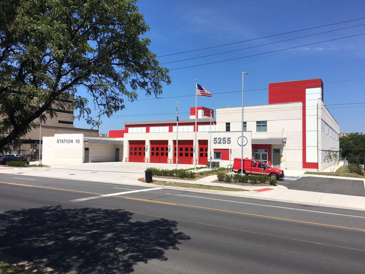 white fire station with red apparatus bays doors and front entrance leading into Alexandria Fire Station